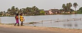 Ivory Coast, Grand Bassam, women walking in front of the lagoon