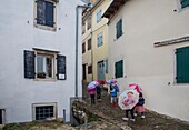 Kroatien, Istrien, Motovun eine Gruppe von Schulkindern im Regen in den Gassen des Dorfes