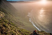 Spanien, Kanarische Inseln, Insel El Hierro, Guarazoca, Mirador de la Pena, erhöhter Blick auf die Nordwestküste bei Sonnenuntergang mit Besuchern