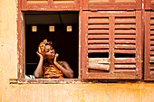 Benin, Ouidah, woman at the window of an old colonial building