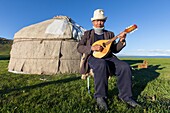 Kyrgyzstan, Naryn Province, Son-Kol Lake, altitude 3000m, Kyrgyz man playing the guitar in front of a yurt