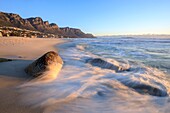 South Africa, Western Cape, Slow motion on a rock at Camps Bay Beach, Cape Town, at the foot of Table Mountain at sunset