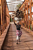 Benin, Grand Popo, woman carrying barks on her head on the old bridge