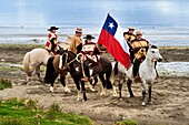 Chile, Los Lagos region, archipelago of Chiloe, Quinchao Island, Curaco de Velez, huasos (riders) with chupalla and manta before a parade, a huaso girl carries the chilean flag