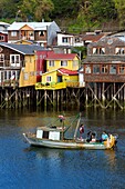 Chile, Los Lagos region, Chiloé Island, town of Castro, wooden fishing houses on stilts called palafitos in the estuary of the Gamboa River, seashell fishing boat