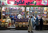 Egypt, Upper Egypt, Nile Valley, Luxor, Egyptians shopping in a grocery store lit up at night with baskets brimming with spices