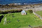 United Kingdom, Scotland, Highlands, Hebrides, Isle of Skye, Elgol village on the shores of Loch Scavaig towards the end of the Strathaird peninsula, children playing rounders in the school garden