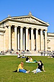 Germany, Bavaria, Munich, Königsplatz, Glyptothek, museum founded in 1830 by the King Louis 1st of Bavaria to welcome its collections of Greek and Roman sculptures, student working leaning against the neoclassical facade