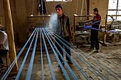 China, Xinjiang autonomous region, Hotan, traditional workshop for silk production, threading, dyeing and weaving, spitting water to lubricate the threads