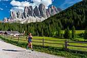 Italien,Trentino-Südtirol,Val di Funes,Dolomitenmassiv,das von der UNESCO zum Weltnaturerbe erklärt wurde,Dolomitengruppe von Puez Geisler,Frau beim Lauftraining