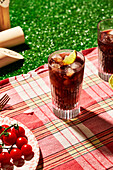 glass of soda on picnic blanket in grass with sunlight,cherry tomatoes and lime,summer mood