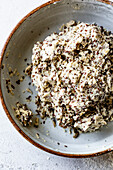 A bowl filled with a thick batter mixture of oats and linseed,which has a textured appearance with a light colour and dark spots