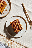 Pumpkin pie square with almond butter on a neutral background with golden forks