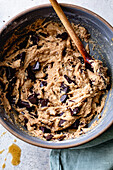 A bowl of cookie dough mixed with chunks of dark chocolate, ready for baking.