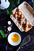 Fresh eggs in a carton being prepared on a black marble base