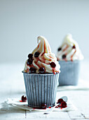 Two frozen yoghurt ice creams, refined with Amarena cherries on a white wooden table