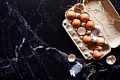 Fresh eggs in carton on black marble background. Horizontal orientation with negative space