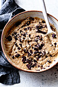 A bowl of biscuit dough with dark chocolate chips mixed in, surrounded by a grey kitchen towel