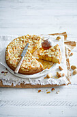 Sliced almond cake with flaked almonds,flavoured with brown vanilla sugar syrup,on a white wooden background