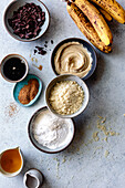 An assortment of baking ingredients, including bananas, chocolate and various powders, on a kitchen table