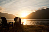 Two Adirondack style wooden lounge chairs at Crescent Lake Lodge at Olympic National Park at sunset.