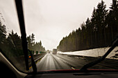 Fahrerperspektive durch die Windschutzscheibe einer winterlichen Autobahn mit Sattelschlepper.