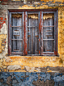 Portugal,Costa Nova. Sehr altes Holzfenster mit Fensterläden an einer bunten Wand mit abblätternder Farbe