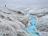 Touristen beim Wandern auf dem Eis. Das braune Sediment auf dem Eis entsteht durch das schnelle Schmelzen des Eises. Landschaft in Grönland in der Nähe von Kangerlussuaq,Königreich Dänemark