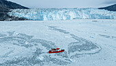 Aerial of a little ship floating between the ice below the Eqi glacier, Western Greenland, Denmark, Polar Regions