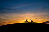 Silhouette of two people carrying baskets at sunset, Nam Cuong sand hill in Ninh Thuan, Vietnam, Indochina, Southeast Asia, Asia