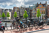 Bicycles with houses by Amstel River in the background, Amsterdam, The Netherlands, Europe