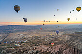 Aerial view of Cavusin and hot air balloons at dawn, Avanos District, Nevsehir Province, Cappadocia, Central Anatolia Region, Anatolia, Turkey, Asia Minor, Asia