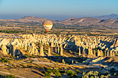 Aerial view of hot air balloon over rock formations in Love Valley at sunrise, Goreme, Goreme Historical National Park, UNESCO World Heritage Site, Cappadocia, Central Anatolia Region, Anatolia, Turkey, Asia Minor, Asia