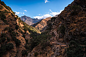 Hiking trail along rugged arid mountain valley of the Sierra Nevada, with Alcazaba in the distance, Andalusia, Spain, Europe