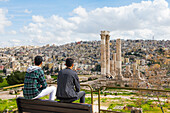 Two young Jordanian men sitting on a bench facing the Temple of Hercules within the Amman Citadel (Jabal al-Qal'a), historic site located on top of a hill in the heart of Amman, Jordan, Middle East