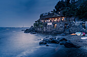 Blick auf Küstenrestaurant in der Nähe der Burg Aragonese in der Abenddämmerung,Hafen von Ischia,Insel Ischia,Kampanien,Italien,Europa