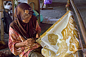 Woman using a pen-like tool (canting) to apply liquid hot wax to create pattern on fabric without preliminary drawing, Nyah Kiok batik house, Lasem, Java island, Indonesia, Southeast Asia, Asia