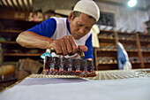 Workers applying wax-resist using a copper plate stamp (cap), Wirakuto batik workshop, Pekalongan, Java island, Indonesia, Southeast Asia, Asia