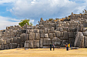 Touristen an der Steinmauer der archäologischen Stätte von Sacsayhuaman,UNESCO-Weltkulturerbe,Cusco,Region Cusco,Peru,Südamerika