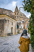 Backview of woman traveller looking at a stone church in the ancient city of Matera, Basilicata, Italy, Europe