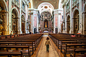 Lisbon, Portugal, March 1 2007, A little girl strolls past wooden benches in the grand baroque interior of Graca church in Lisbon, showcasing stunning rococo artwork.