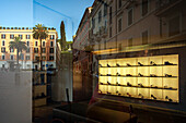 Piazza di Spagna's vibrant reflections blend with the stylish shoe display in a shop window on a sunny day in Rome, Italy.