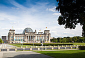 The Reichstag building in Berlin stands prominently with its iconic dome against a clear sky, inviting visitors to explore its history.