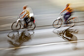 Motion blur image of cyclists riding through the city at night, showcasing speed, movement, and urban energy.