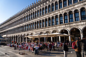 People dining al fresco in front of the Procuratie Vecchie in St. Mark's Square in Venice, Italy.