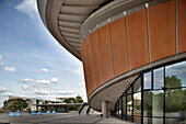 Visitors admire the unique design of the House of World Cultures in Berlin, showcasing modern architecture surrounded by green spaces.