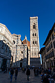 Touristen in der Pizza San Giovanni vor dem Dom und dem Campanile in Florenz,Italien. Das Baptisterium befindet sich auf der linken Seite.