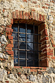 Barred window in a building in the medieval walled town of Monteriggioni, Sienna, Tuscany, Italy.