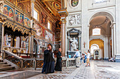 Rome, Italy, July 22 2017, Two priests interact with visitors in the historic Saint John Lateran basilica in Rome, surrounded by magnificent architecture.