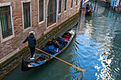 Ein Paar Gondeln befördert Touristen in einem Kanal in Venedig,Italien.